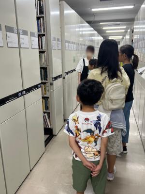 バックヤードツアー開始して書棚の前で話を聞いている写真