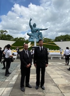 式典当日、平和祈念像の前に立つ渡辺議長(左)と長友市長