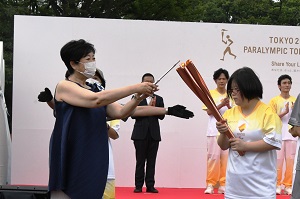 東京都知事がグループランナーのトーチに点火している写真