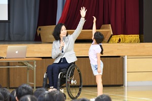 手を挙げた時の高さを比べるマセソン美季氏と児童の写真