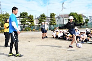 児童がシュートしている様子を見守る梶山さんの写真