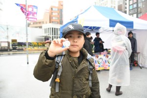 完成した缶バッチを見せる子どもの写真